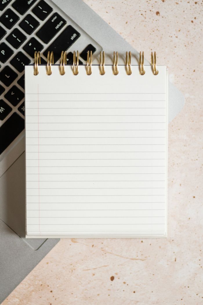 A vertical shot of a blank spiral notepad on a laptop keyboard, top view.